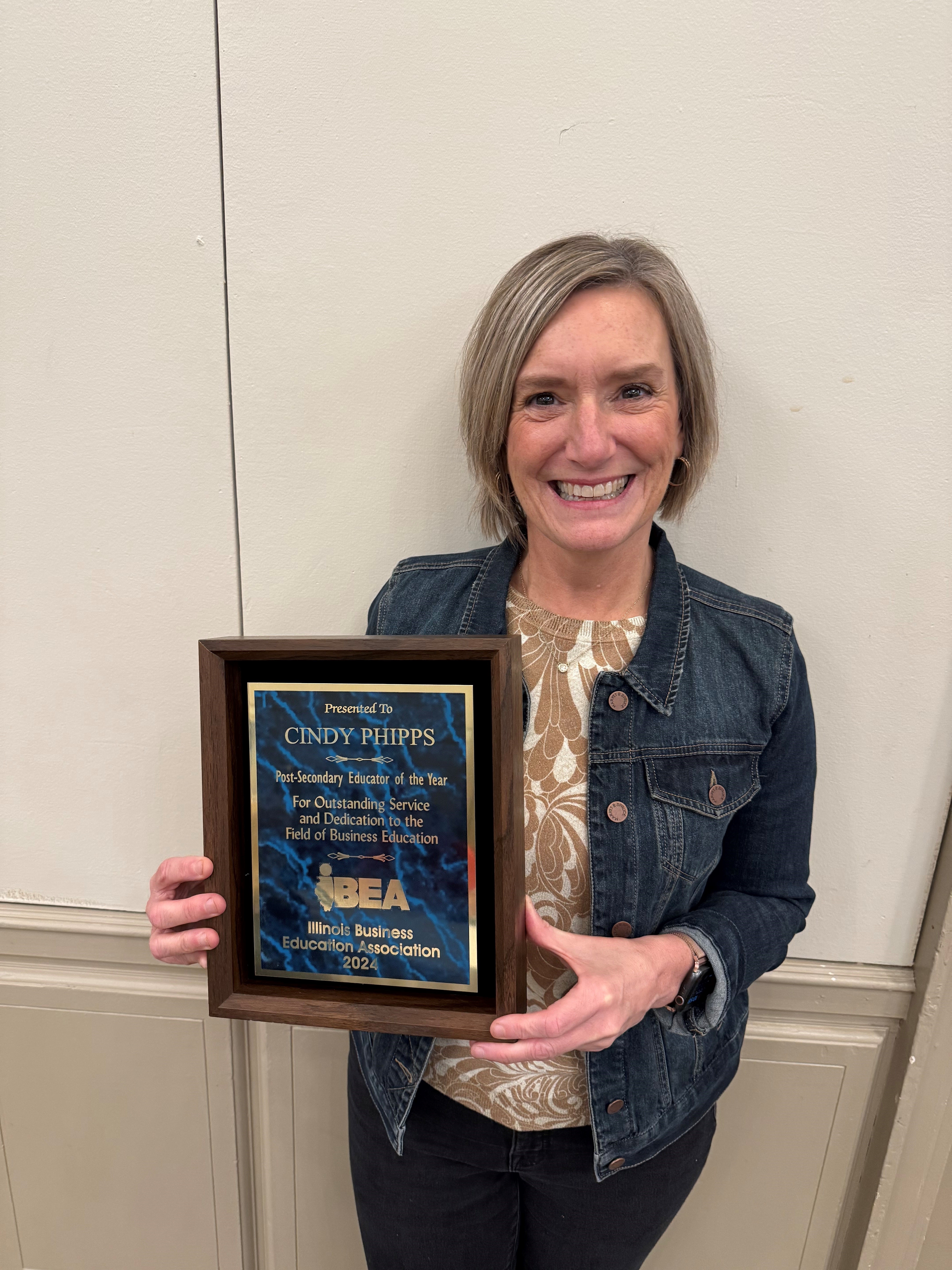 A Lake Land College instructor holding an award