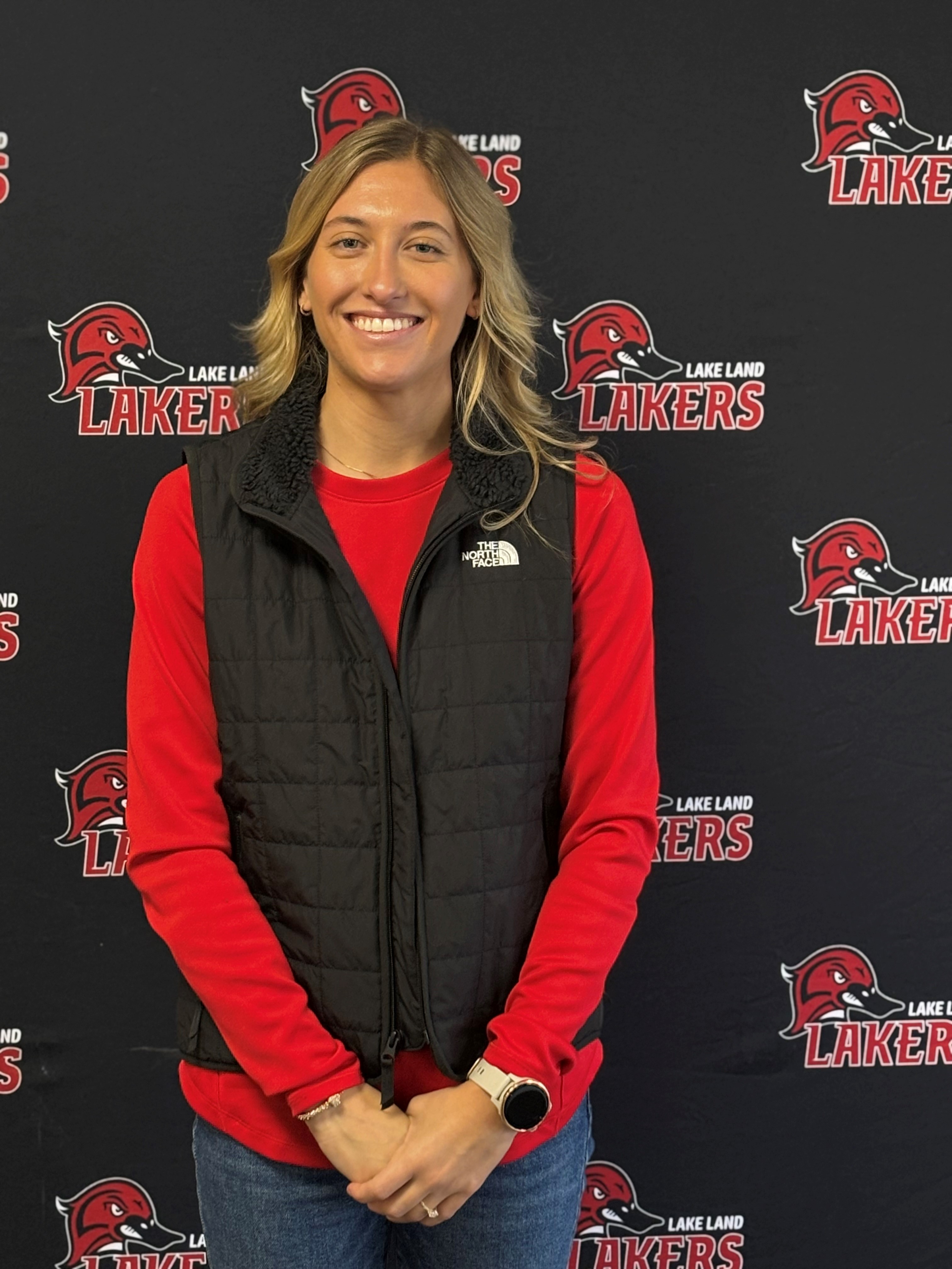 The Lake Land College Cross Country Coach standing in front of a Laker Athletics backdrop