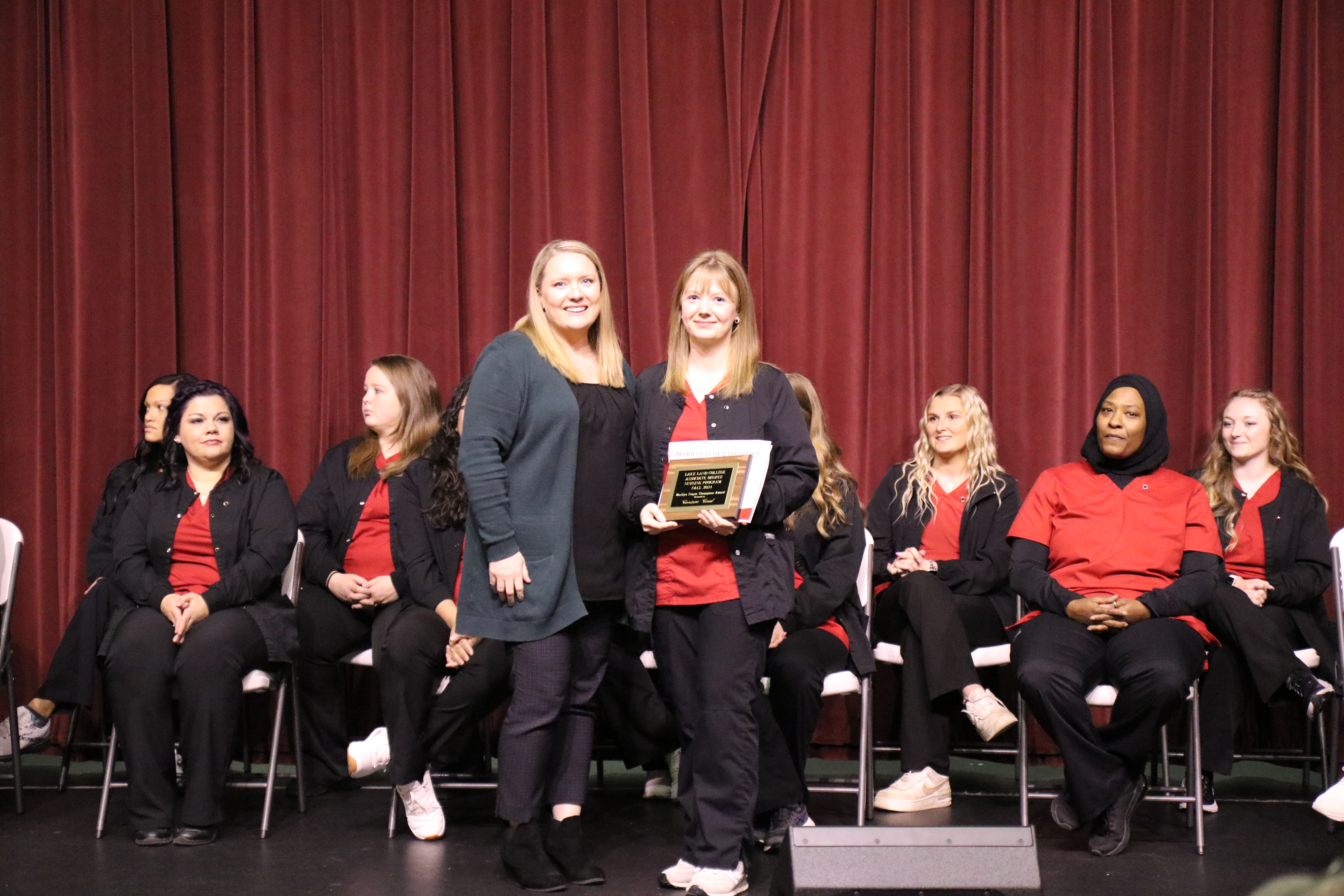 A nursing instructor presenting an award to a graduating student during a pinning ceremony